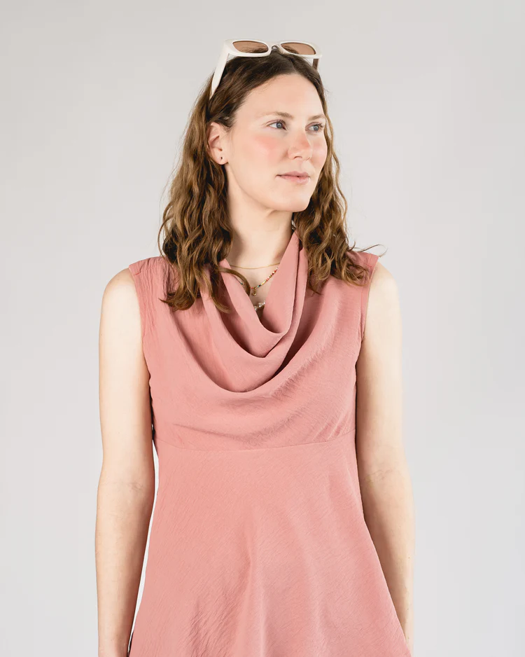 Woman wears dusky pink cowl top with snaps at shoulders